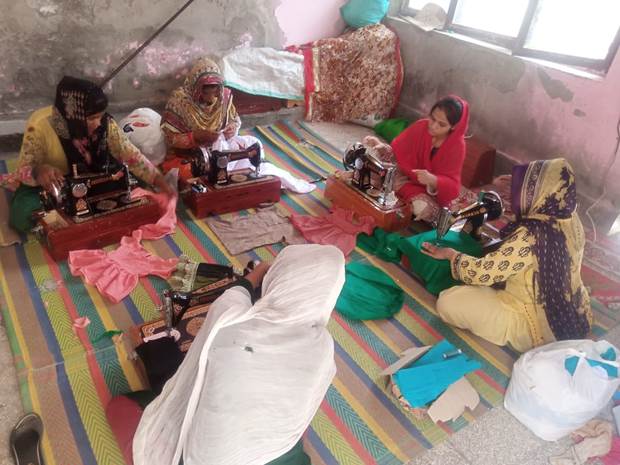 Women sitting on the floor with sewing machines

Description automatically generated
